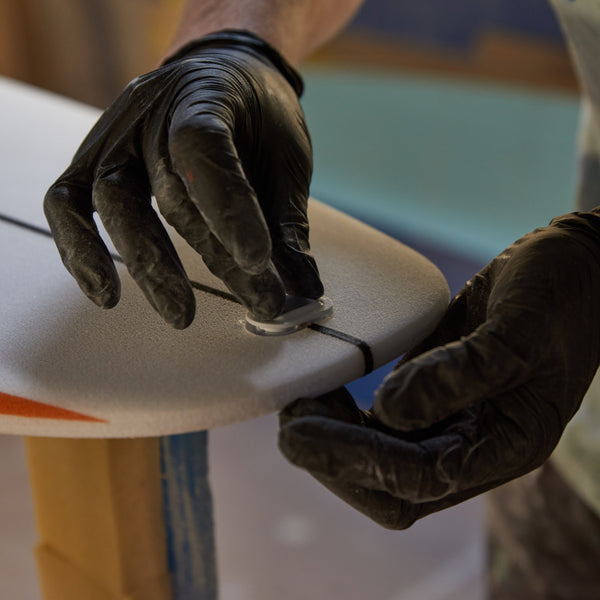 Installing a fin plug on the surfboard tail.
