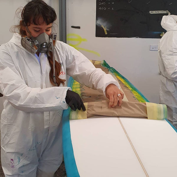 Removing the masking tape after finishing a spray on the finished board - The Surfboard Studio